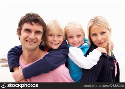 Young Family Sitting On Winter Beach