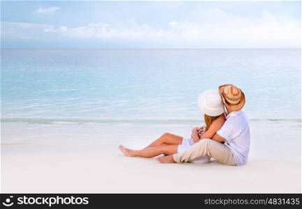 Young family spending summer vacation on romantic beach resort, sitting and enjoying seascape, romance and affection concept
