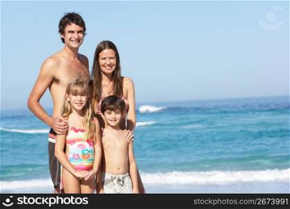 Young Family Standing On Sandy Beach on Holiday