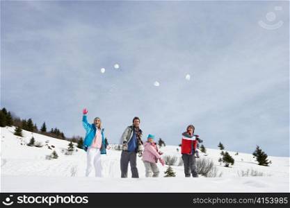 Young Family Throwing Snowballs On Winter Vacation