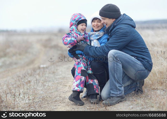 young family with a child playing on winter field