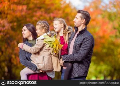 Young family with cute little kids in autumn park on sunny day. Portrait of happy family of four in autumn day. Portrait of happy family of four in autumn day