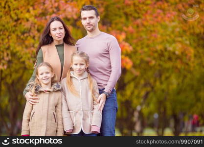 Young family with cute little kids in autumn park on sunny day. Portrait of happy family of four in autumn day