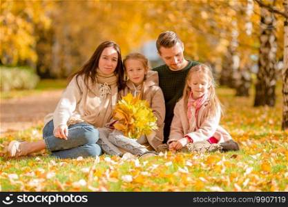 Young family with cute little kids in autumn park on sunny day. Portrait of happy family of four in autumn day