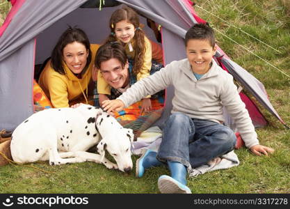 Young Family With Dog Relaxing Inside Tent On Camping Holiday