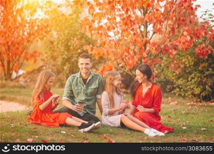 Young family with little kids in autumn park on sunny day. Family autumn portrait. Portrait of happy family of four in autumn day