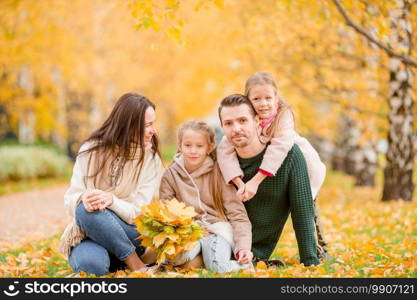 Young family with little kids in autumn park on sunny day. Family autumn portrait. Portrait of happy family of four in autumn day