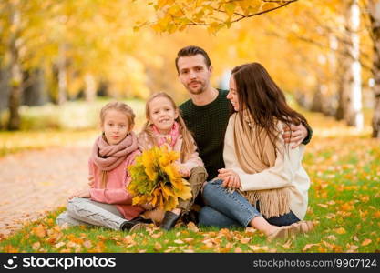 Young family with little kids in autumn park on sunny day. Family autumn portrait. Portrait of happy family of four in autumn day