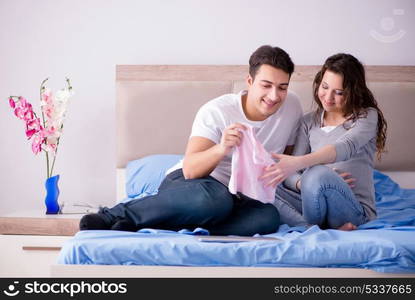 Young family with pregnant wife expecting baby in bed