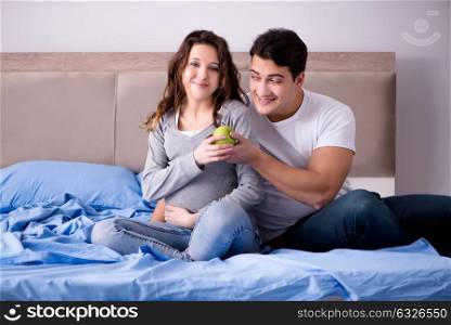 Young family with pregnant wife expecting baby in bed