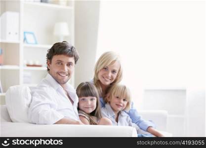 Young family with two children on a white sofa at home
