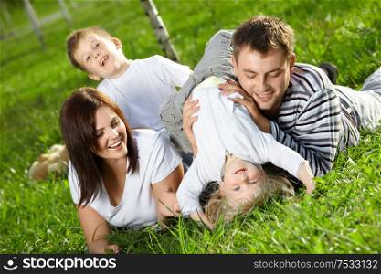 Young family with two small children frolics on a lawn