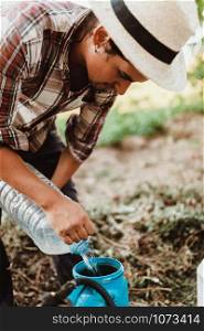 Young farmer preparing organic fertilizer with manual pump tank wearing an old hat and plaid shirt