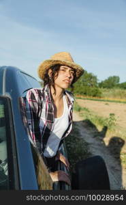 Young farmer woman in a van looking out at crop field