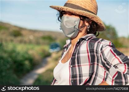 Young farmer woman with straw hat and surgical mask resting