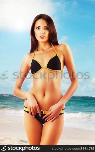 Young fashion brunette attractive woman in swimsuit on the beach