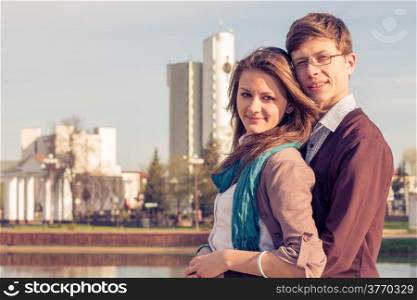 Young fashion elegant stylish couple posing in a European city park. Hipster cute girl with handsome man having fun outdoor.