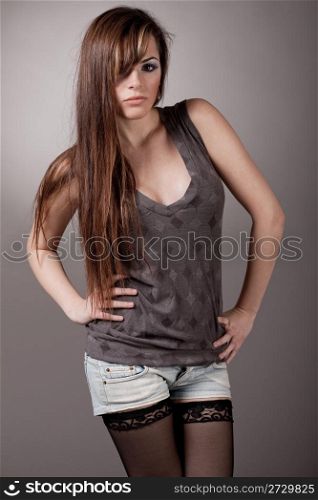 Young fashion model with a long hair posing at the camera, indoor studio