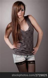 Young fashion model with a long hair posing at the camera, indoor studio