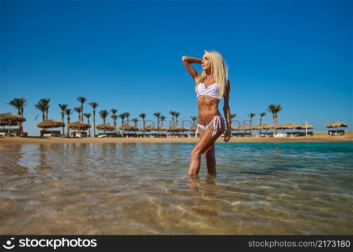 Young fashion woman standing in water on the beach.. Young fashion woman standing in water on the beach