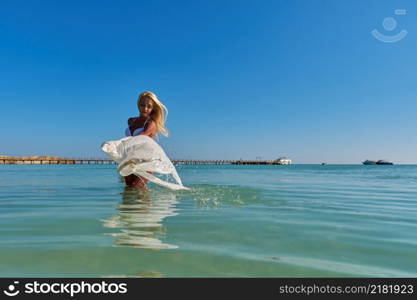 Young fashion woman standing in water on the beach.. Young fashion woman standing in water on the beach