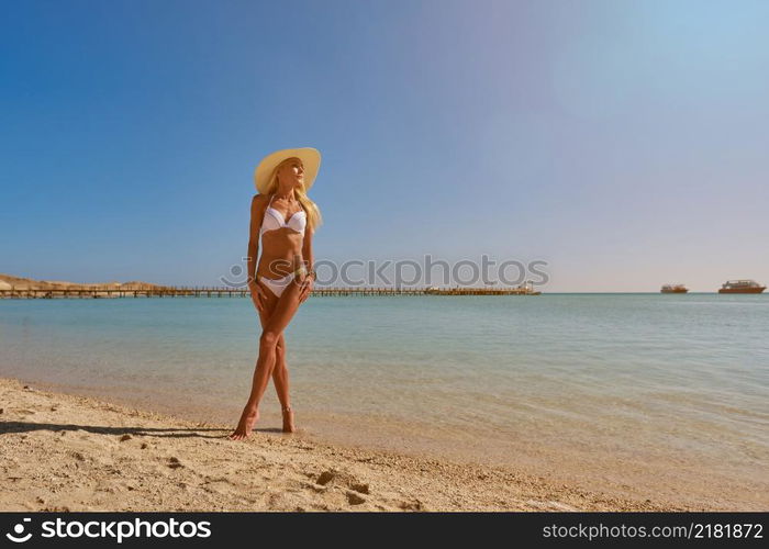 Young fashion woman standing near water on the beach.. Young fashion woman standing near water on the beach