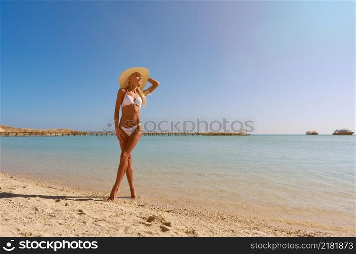 Young fashion woman standing near water on the beach.. Young fashion woman standing near water on the beach