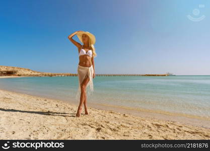 Young fashion woman standing near water on the beach.. Young fashion woman standing near water on the beach