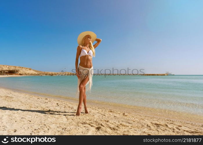 Young fashion woman standing near water on the beach.. Young fashion woman standing near water on the beach