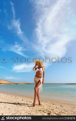 Young fashion woman standing near water on the beach.. Young fashion woman standing near water on the beach