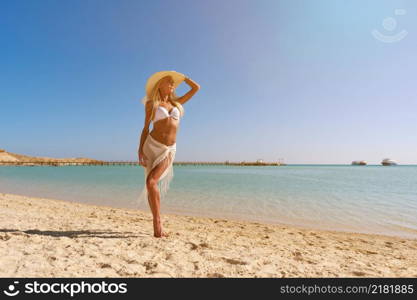 Young fashion woman standing near water on the beach.. Young fashion woman standing near water on the beach