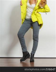Young fashionable girl wearing lemon jacket and shoes on platform. Preparing herself clothes. Fashion in winter time.