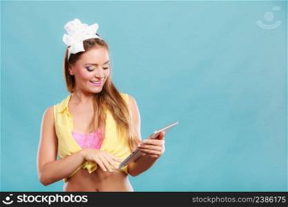 Young fashionable pin up girl using computer tablet browsing surfing the internet. Retro vintage old fashioned woman on blue background. Fashion and modern technology.