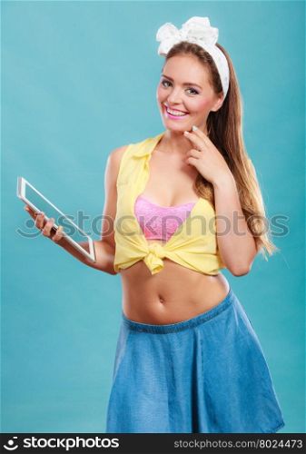 Young fashionable pin up girl using computer tablet browsing surfing the internet. Retro vintage old fashioned woman on blue background. Fashion and modern technology.