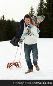 Young Father And Daughter In Snow With Sled