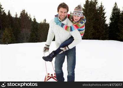 Young Father And Daughter In Snow With Sled