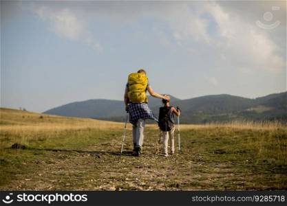 Young father and his cute daughter enjoy hiking on a sunny day