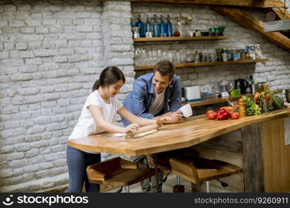 Young father and his cute daughter making dough at rustic home kitchen