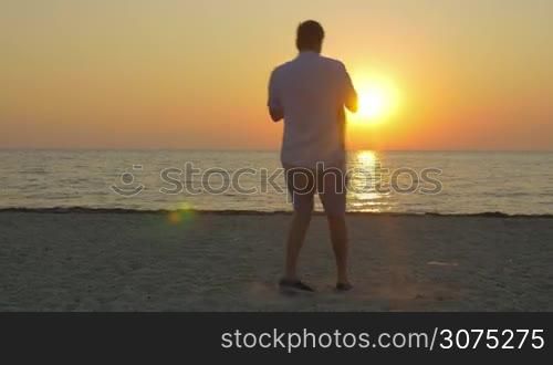Young father and little son having fun on the beach. Dad spinning kid on the background of sea and golden sunset
