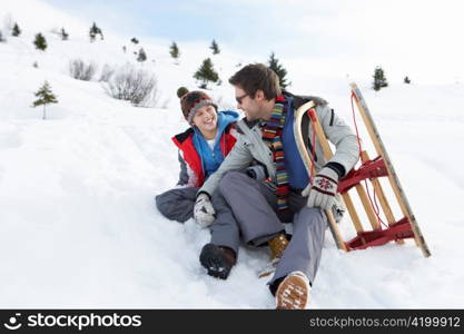 Young Father And Son In Snow With Sled