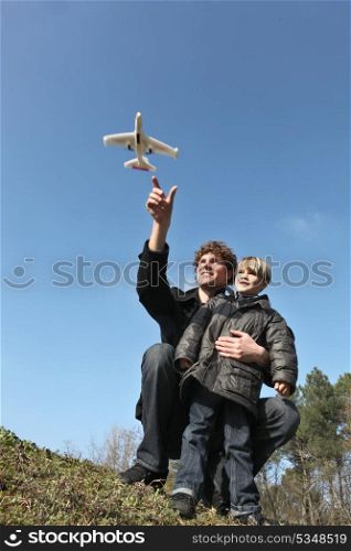 young father and son playing with toy plane outdoors