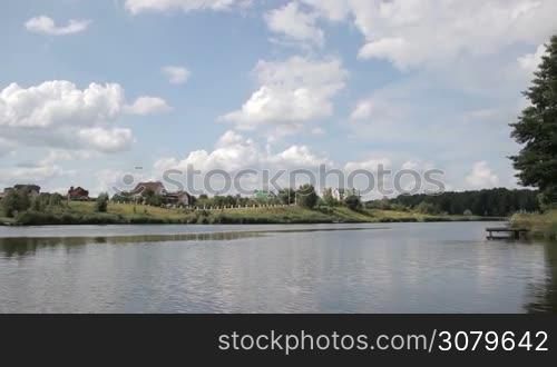 Young father and teenager fishing together on the lake from wooden pier over beautiful rural landscape background. Skillful dad casting fishing rod while fishing together with teenage son in pond on sunny summer day. Slow motion.