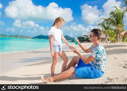 Young father applying sun cream to daughter nose on the beach. Sun protection. Young father applying sun cream to daughter