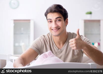 Young father enjoying time with newborn baby at home