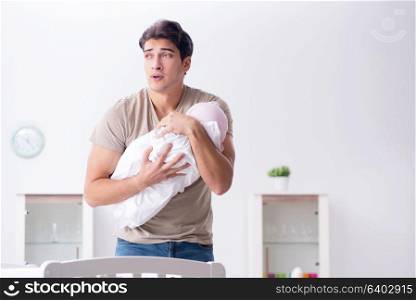 Young father enjoying time with newborn baby at home