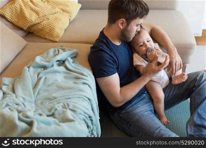 Young father feeding his baby with nursing bottle