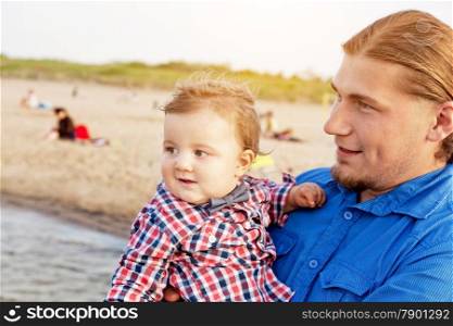 Young father holding his child on the beach having fun together. Son and parent bond