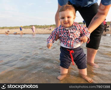 Young father holding his child over sea water having fun together. Son and parent bond