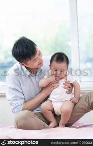 Young father playing with his baby on the bed