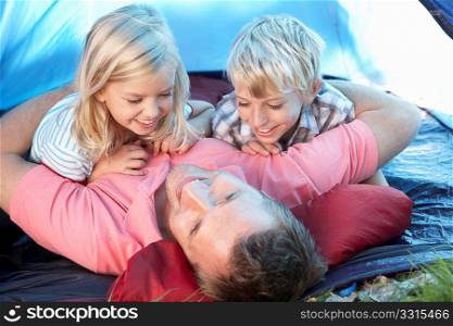 Young father plays with children in tent